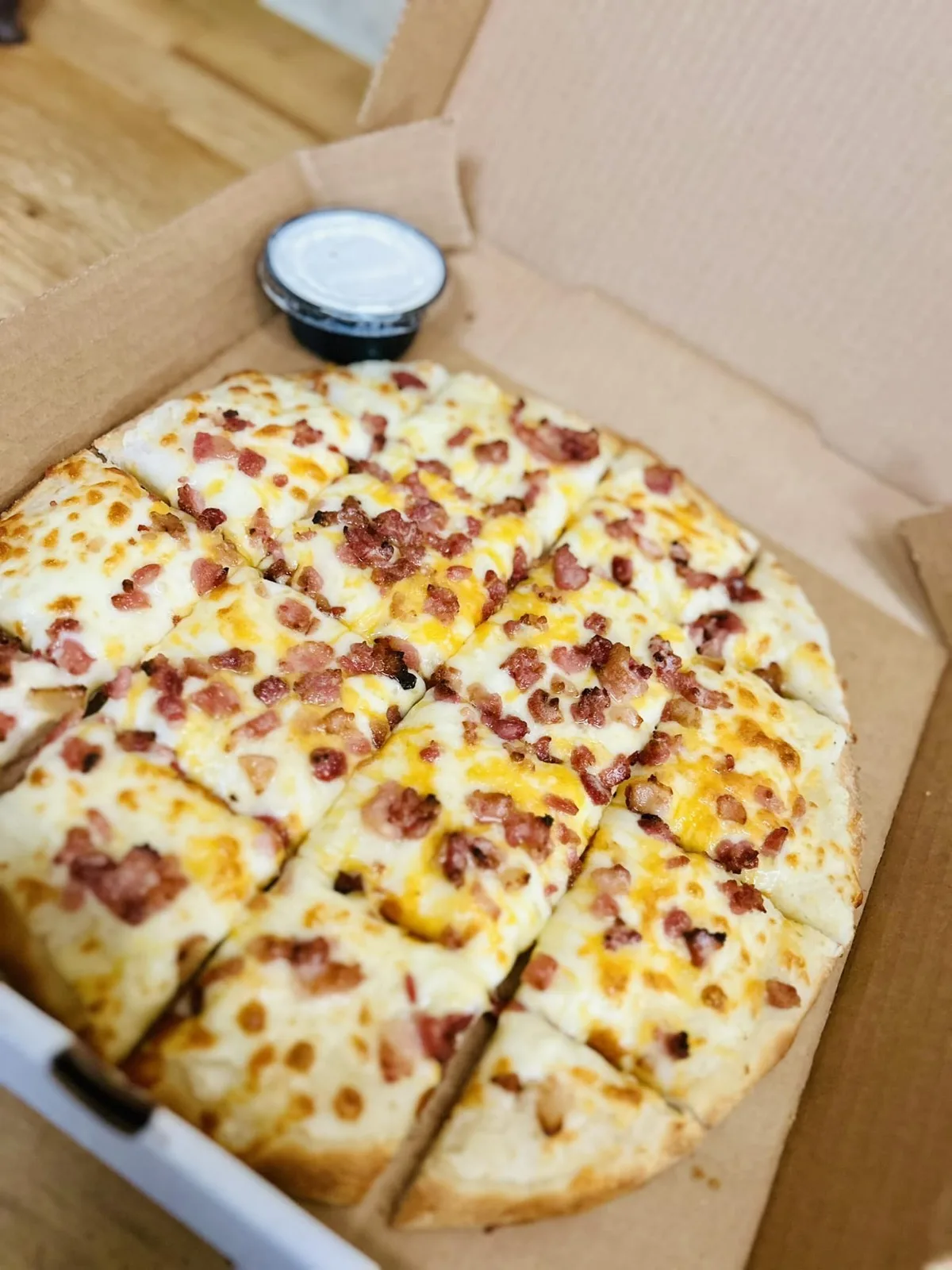 Bacon-cheddar pizza in the box with a side of ranch
